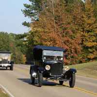 Antique cars driving towards Tupelo on a fall day.